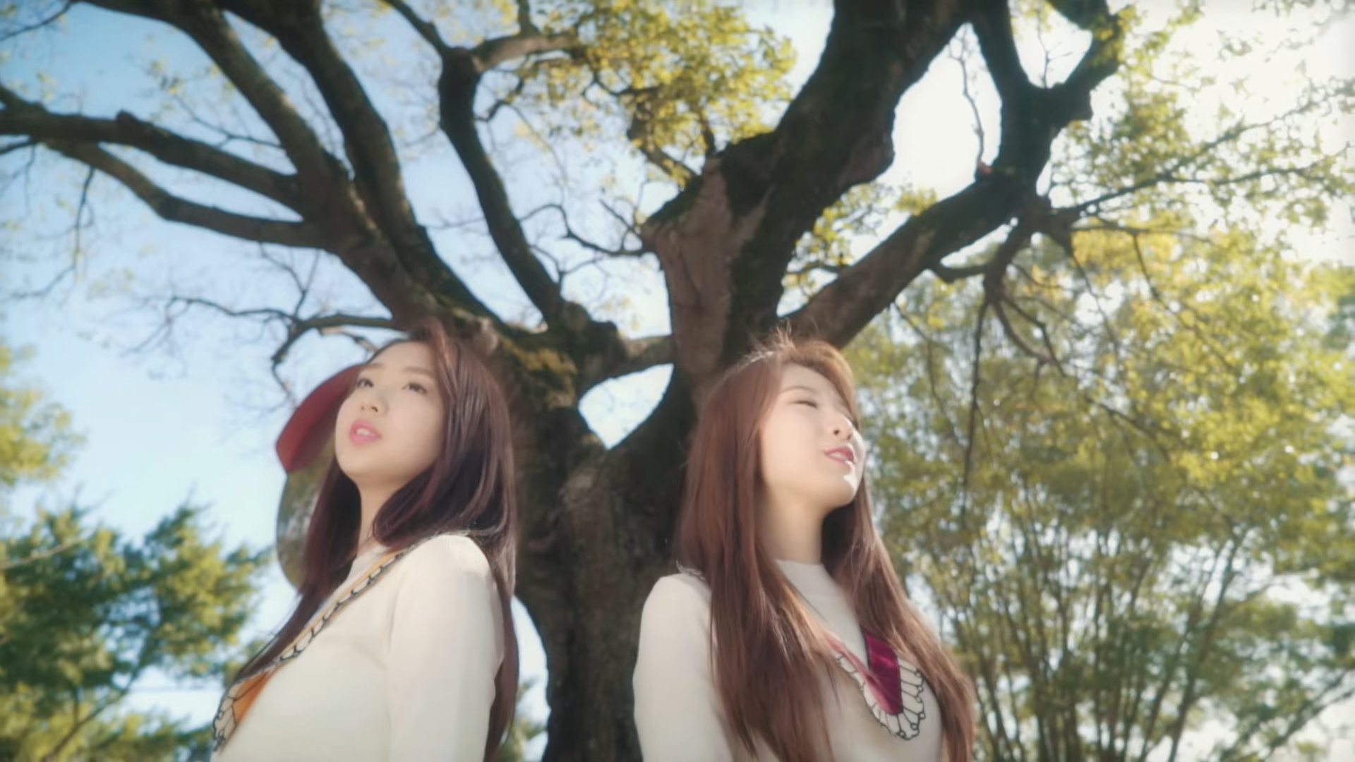 Haseul and Yeojin standing in front of a large tree.